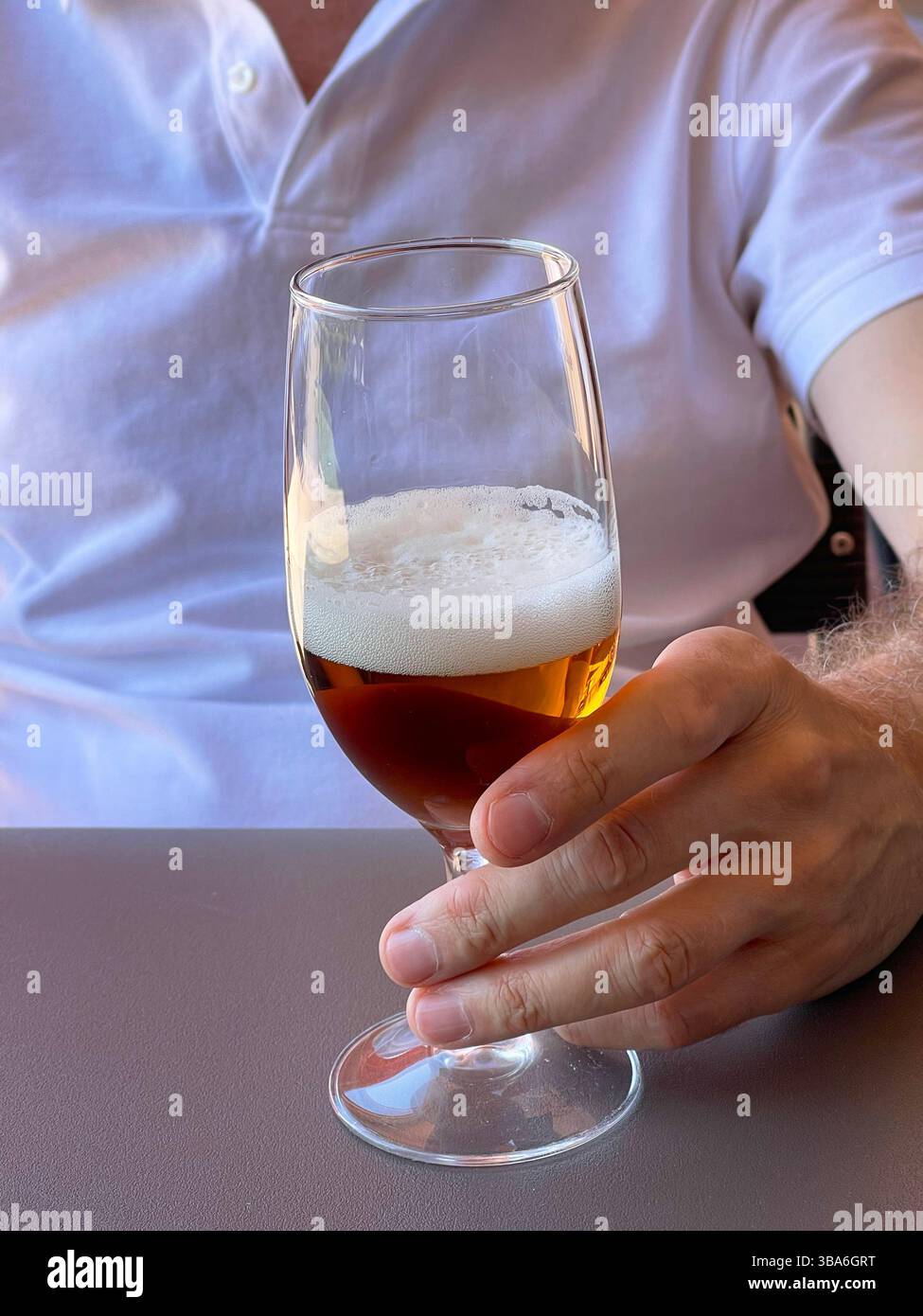 Man’s hand holding a glass of beer. - Smartphone Captured Stock Image
