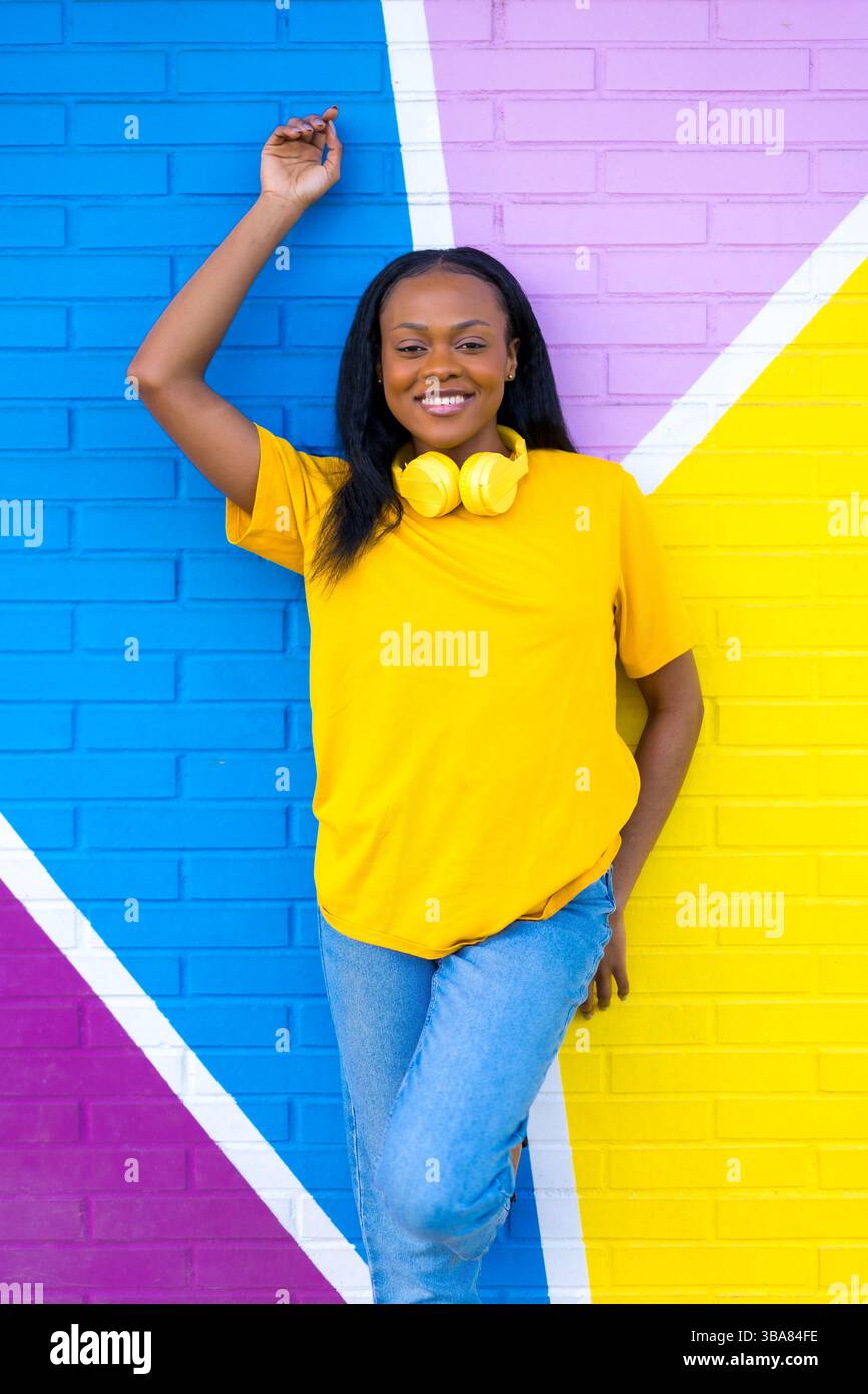 Vertical portrait of a young african woman smiling at camera next to ...