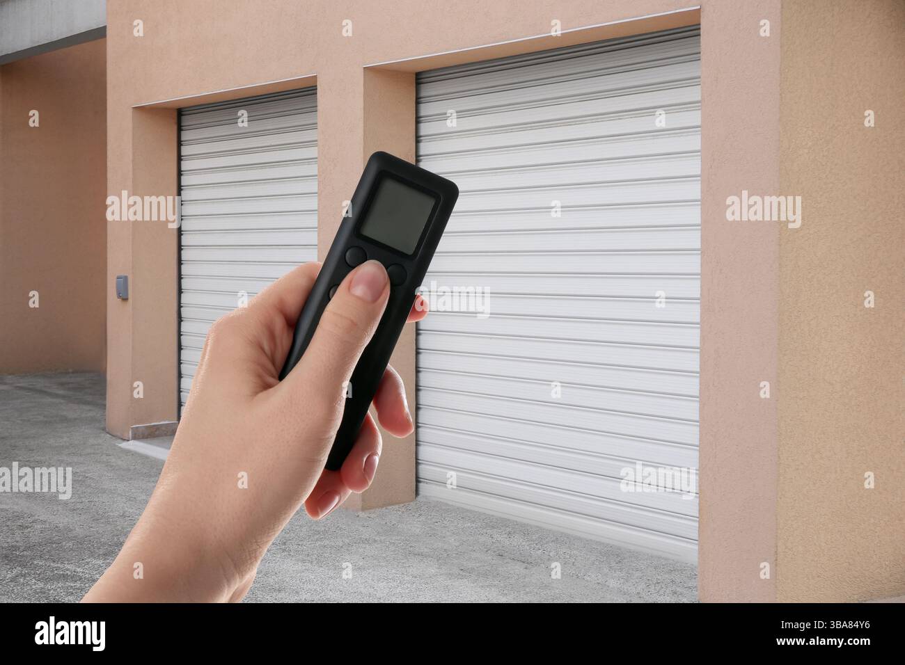 Woman using remote to control roller door outdoors, closeup Stock Photo
