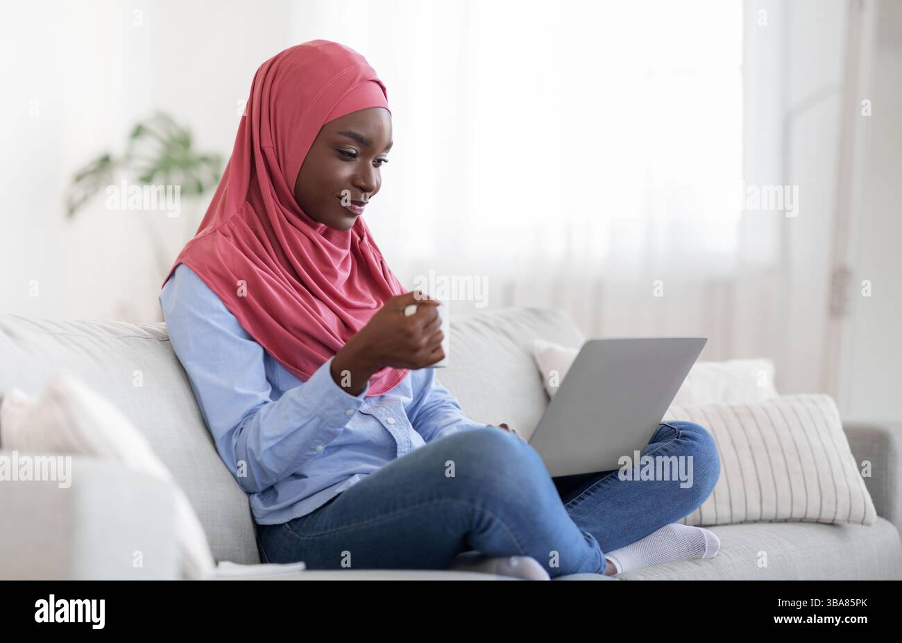 Domestic Relax. Black Muslim Lady In Hijab Using Laptop And Drinking ...