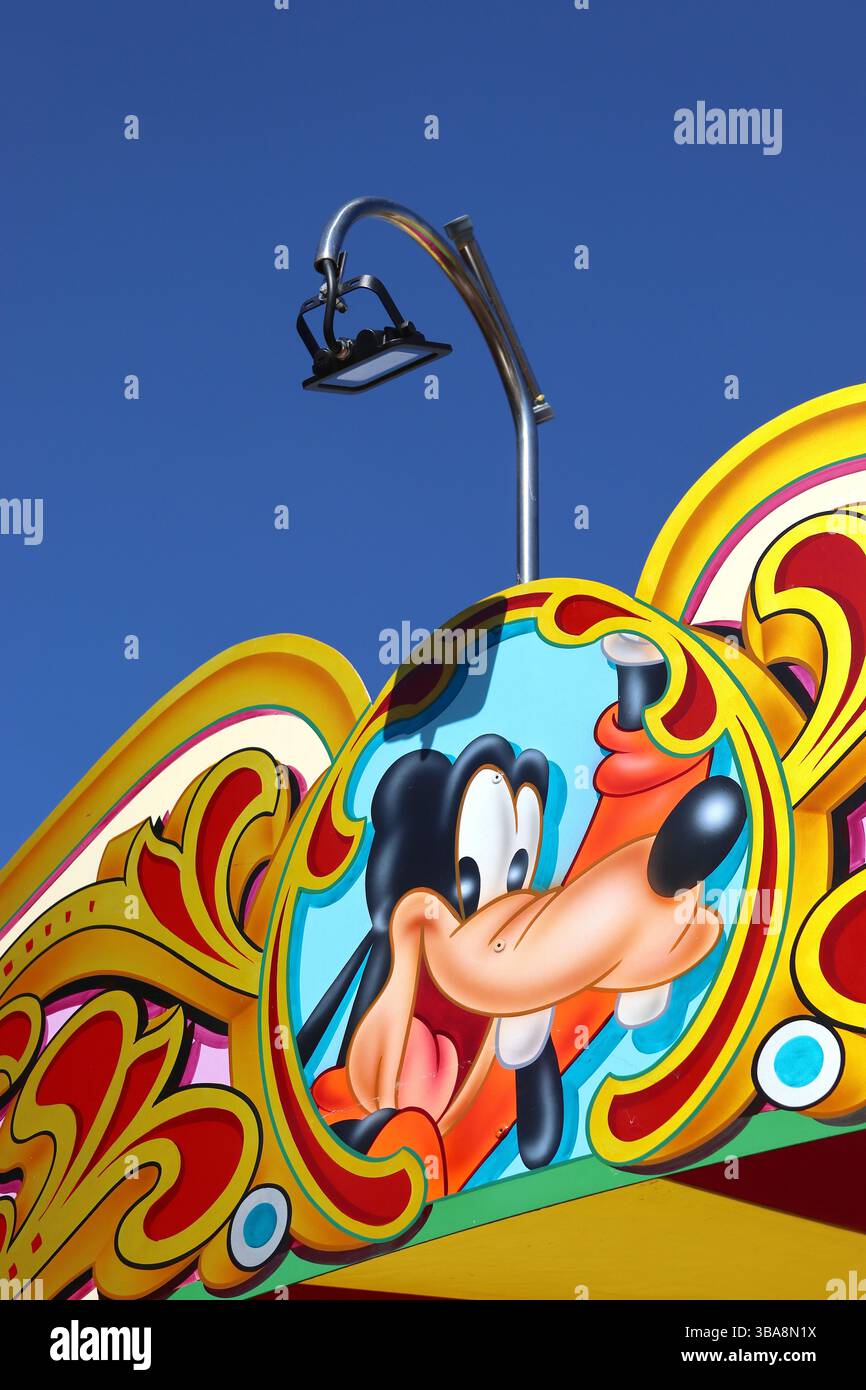 A colourful fairground ride header panel with decorative graphics and a portrait of a cartoon character. Stock Photo