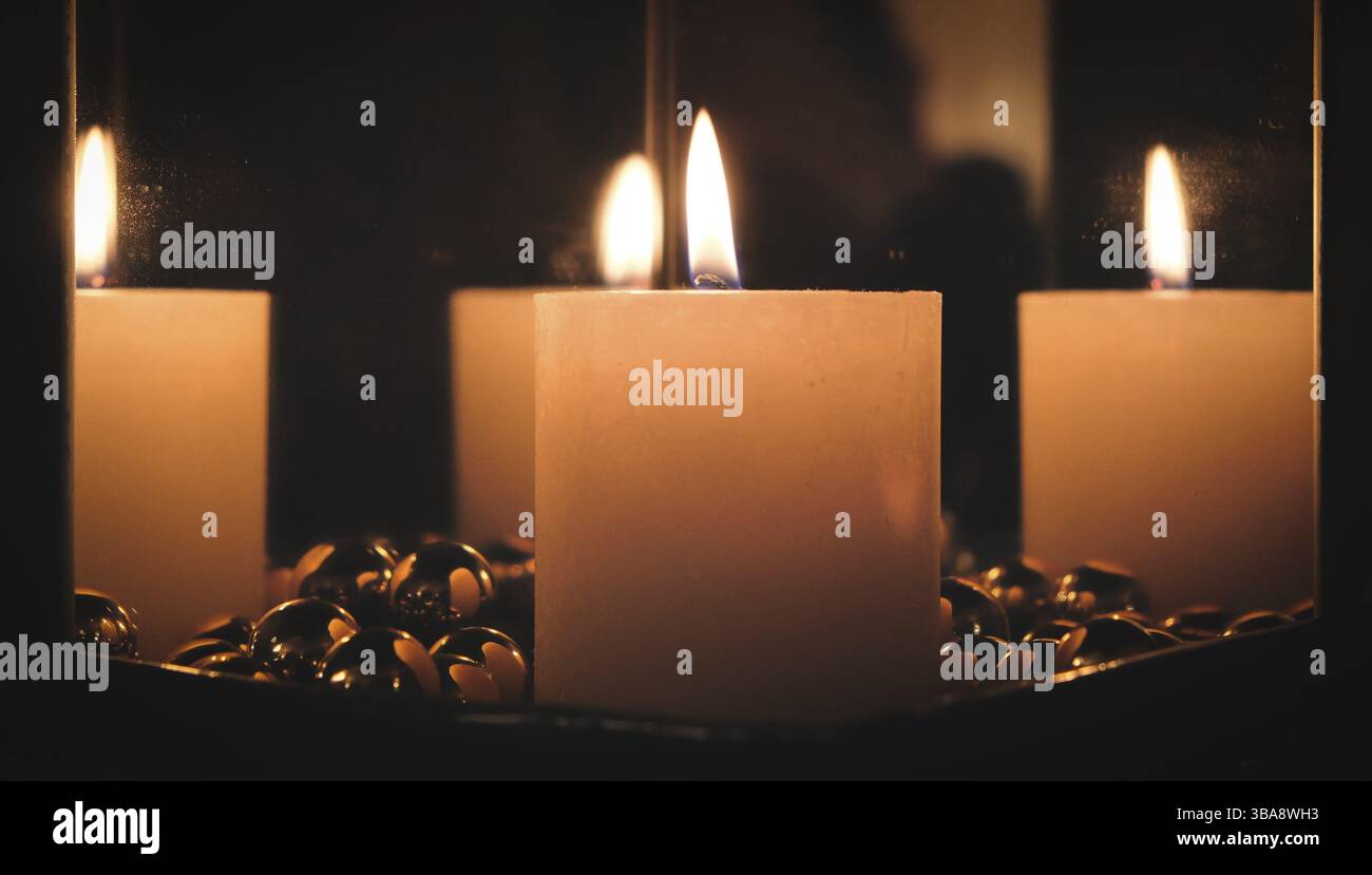 Christmas candle between mirrors on a stove Stock Photo