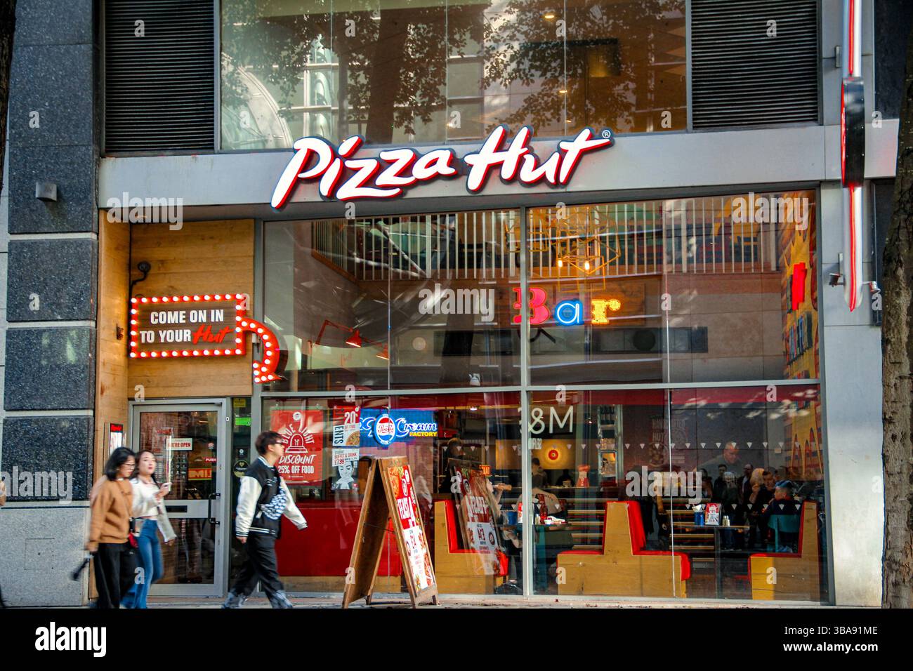 Corporation St, Manchester, UK - 11.16.2024: A Pizza Hut storefront on a busy street, with people passing by on a sunny day. Stock Photo
