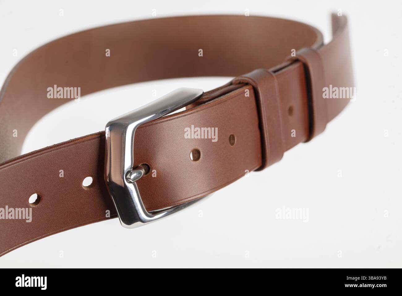 Part of a light brown leather classic belt with a buckle on a grey background Stock Photo
