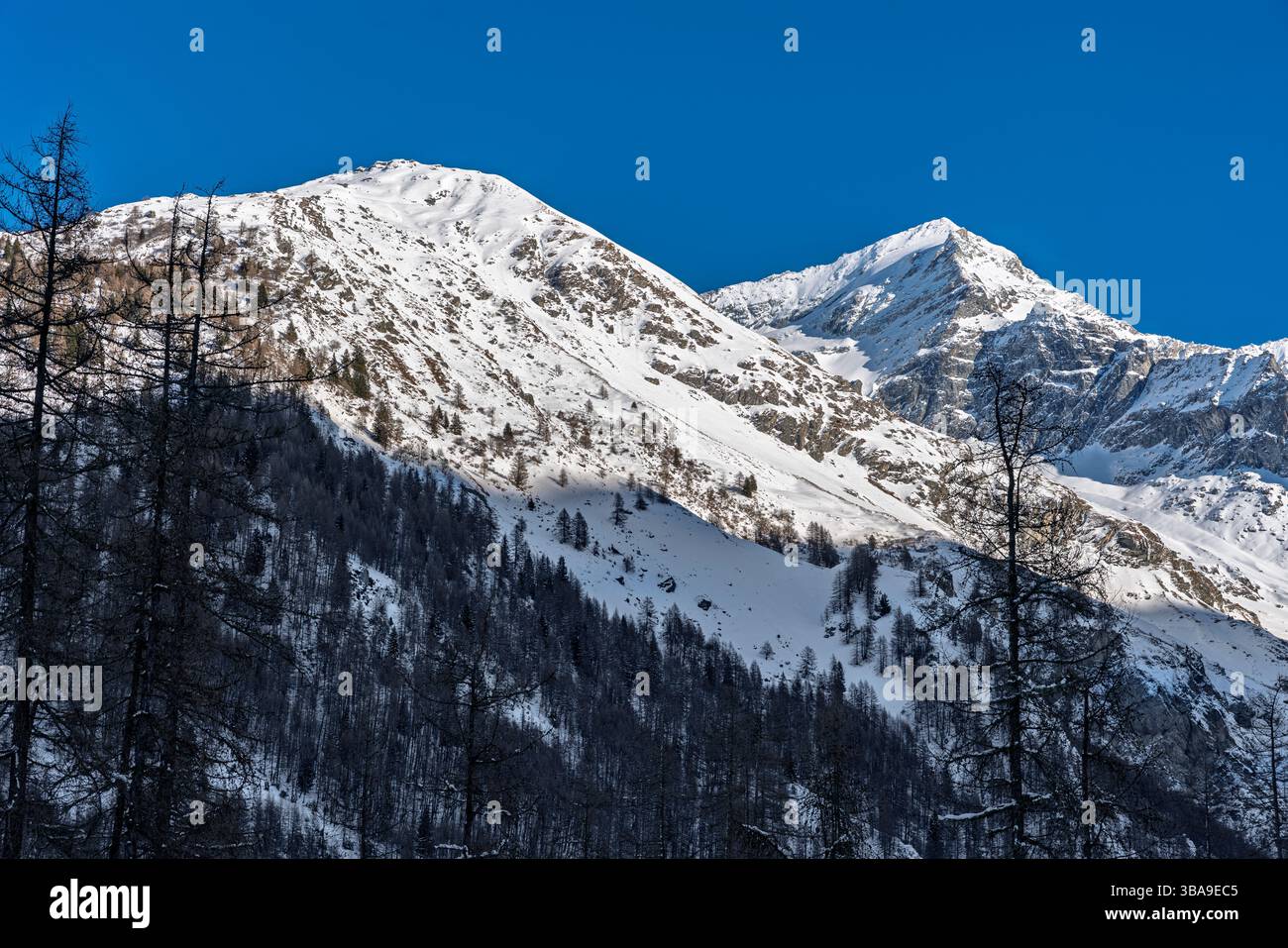 Sloping Ridges A layered mountain slope stretches wide under a deep blue sky, its ...