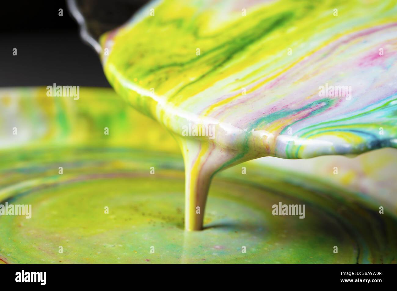 Acrylic paint flows out of the plate. Creative process Stock Photo - Alamy