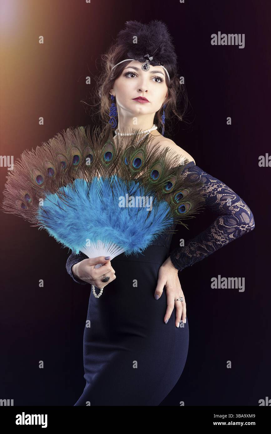 Retro portrait of a woman. Beautiful girl with a fan in the style of the 20s or 30s. Old fashionable finger wave make up and hairstyle Stock Photo