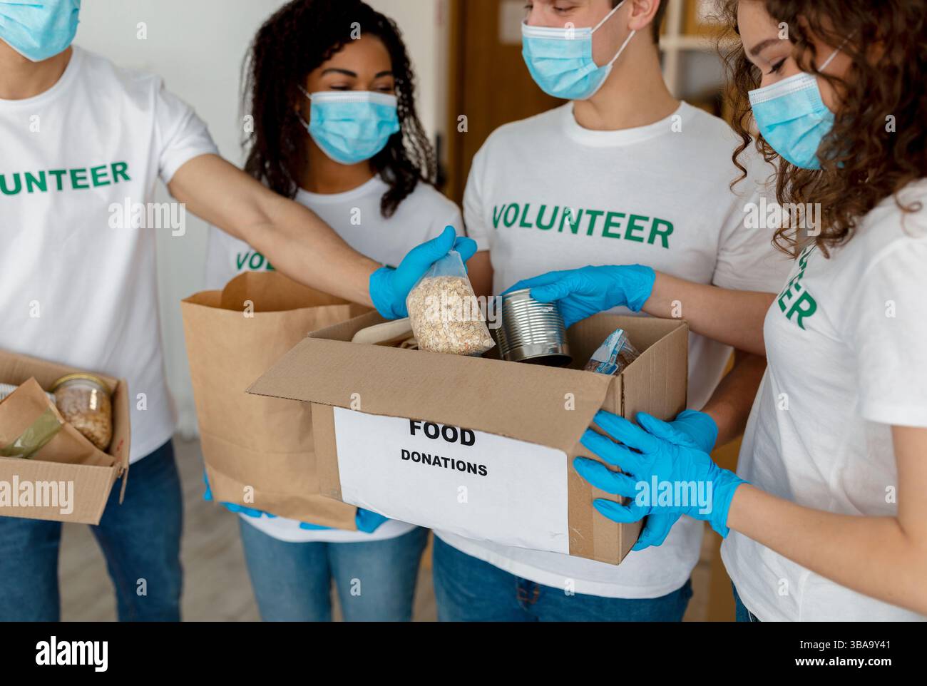 International group of volunteers sorting donated food in boxes ...