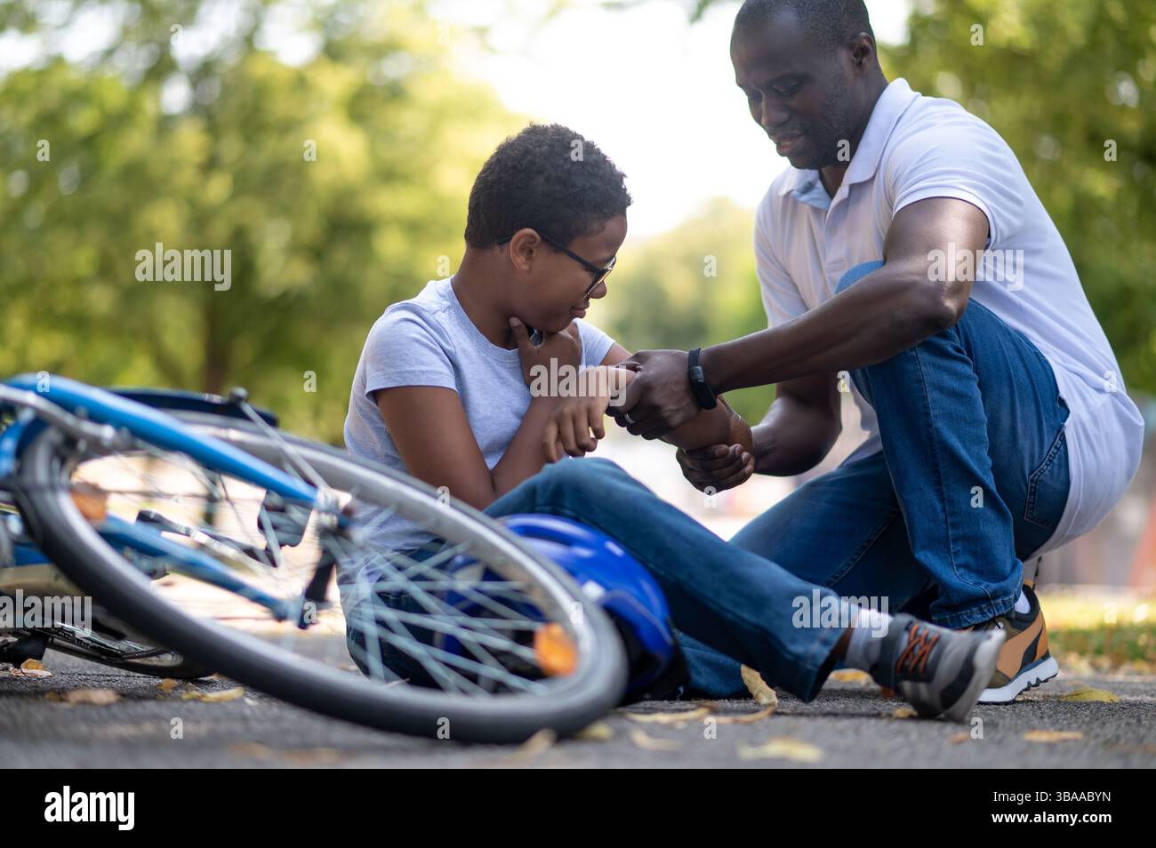 His Falling Falling down. Dad helping his son after falling down from a bike Stock ...
