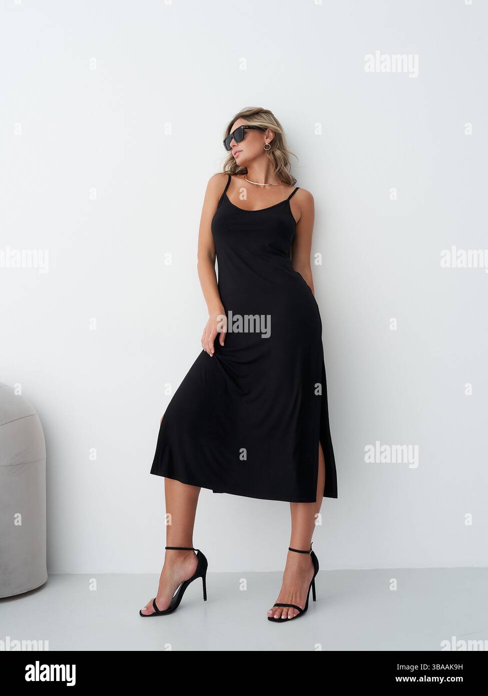Woman in a black dress poses in a minimalist indoor setting with modern ...