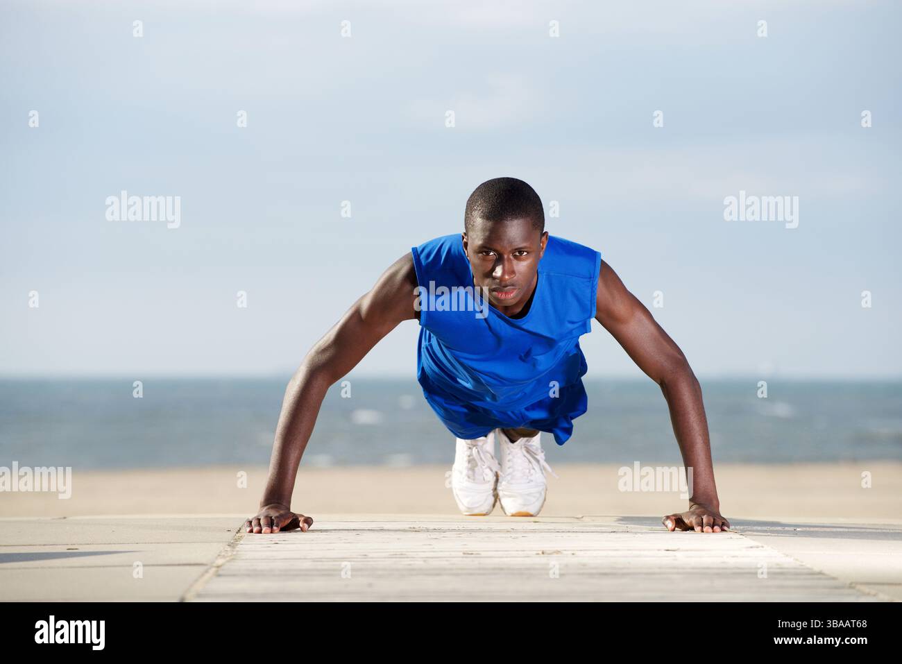 Portrait of healthy young man doing push ups on the beach Stock Photo ...