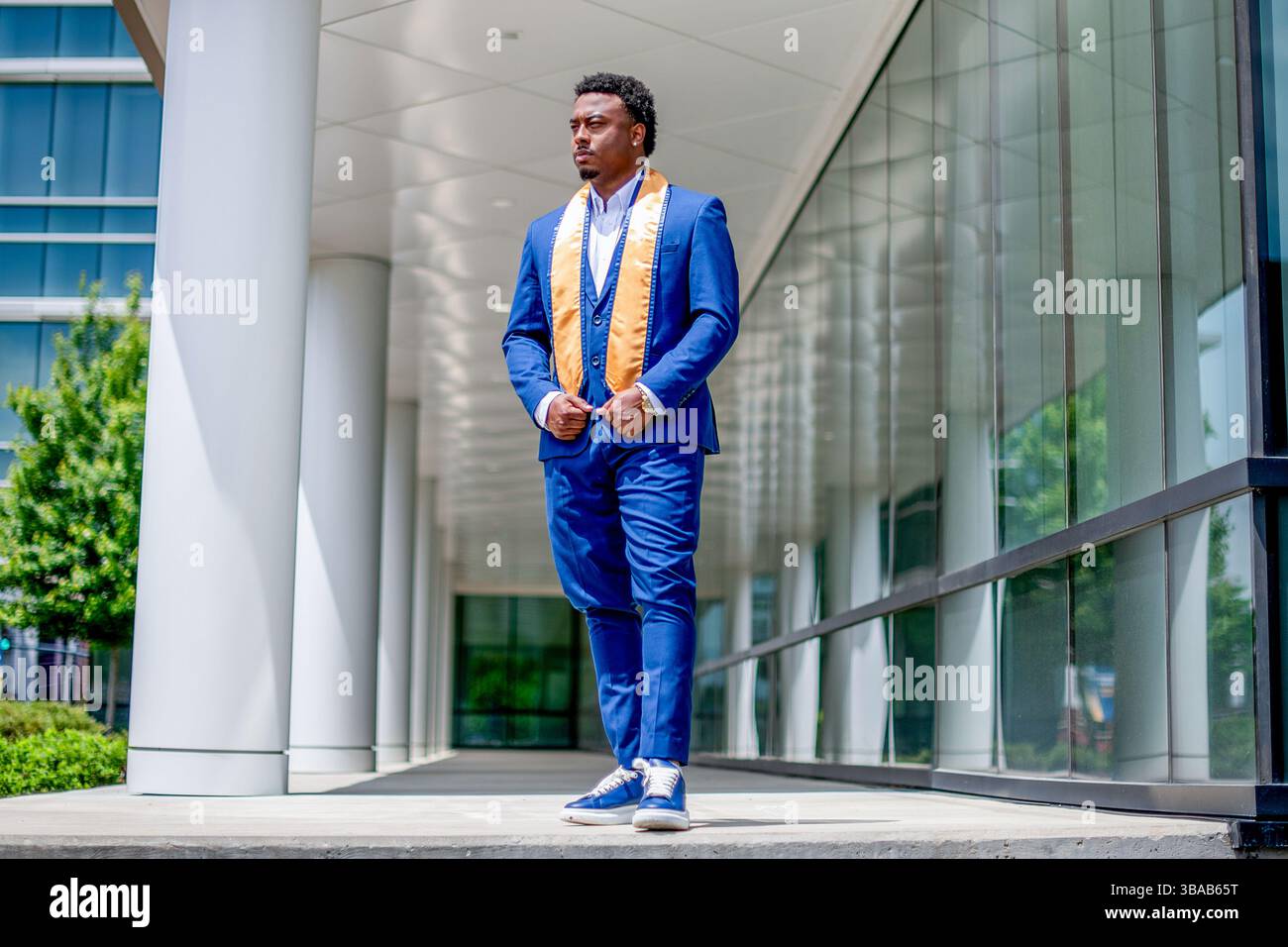 African American man wearing blue suit and graduation stole looking ...