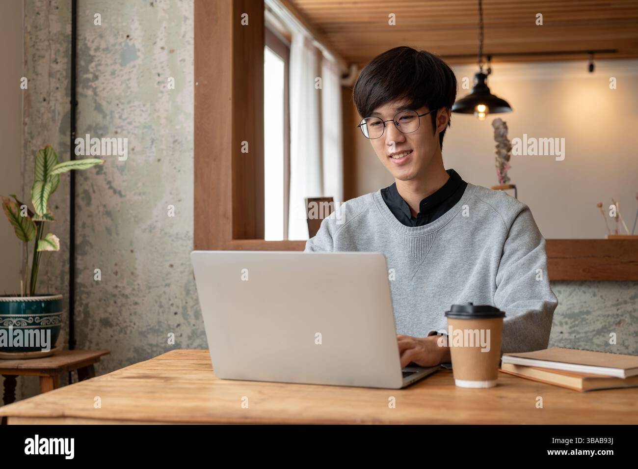 A happy and smart young Asian male college student in casual clothes ...