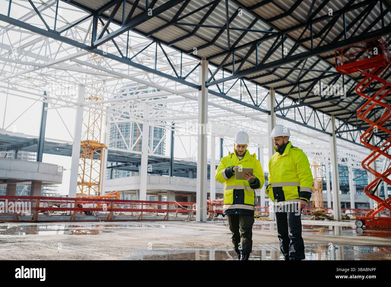 Construction managers using digital tablet on site, reviewing project plans. Stock Photo