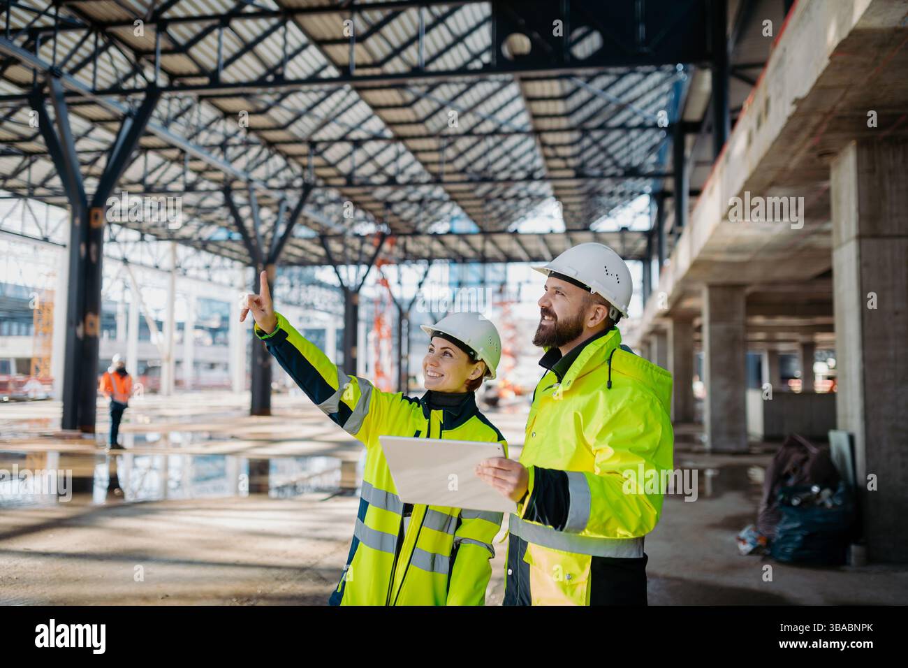 Engineers discussing construction plans using a tablet on site. Stock Photo
