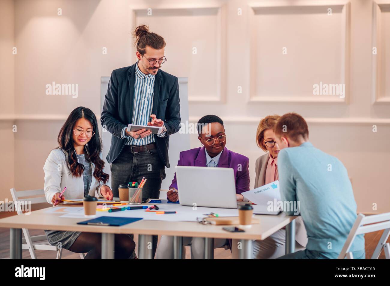 Diverse employees gathered in the office brainstorming while discussing ...