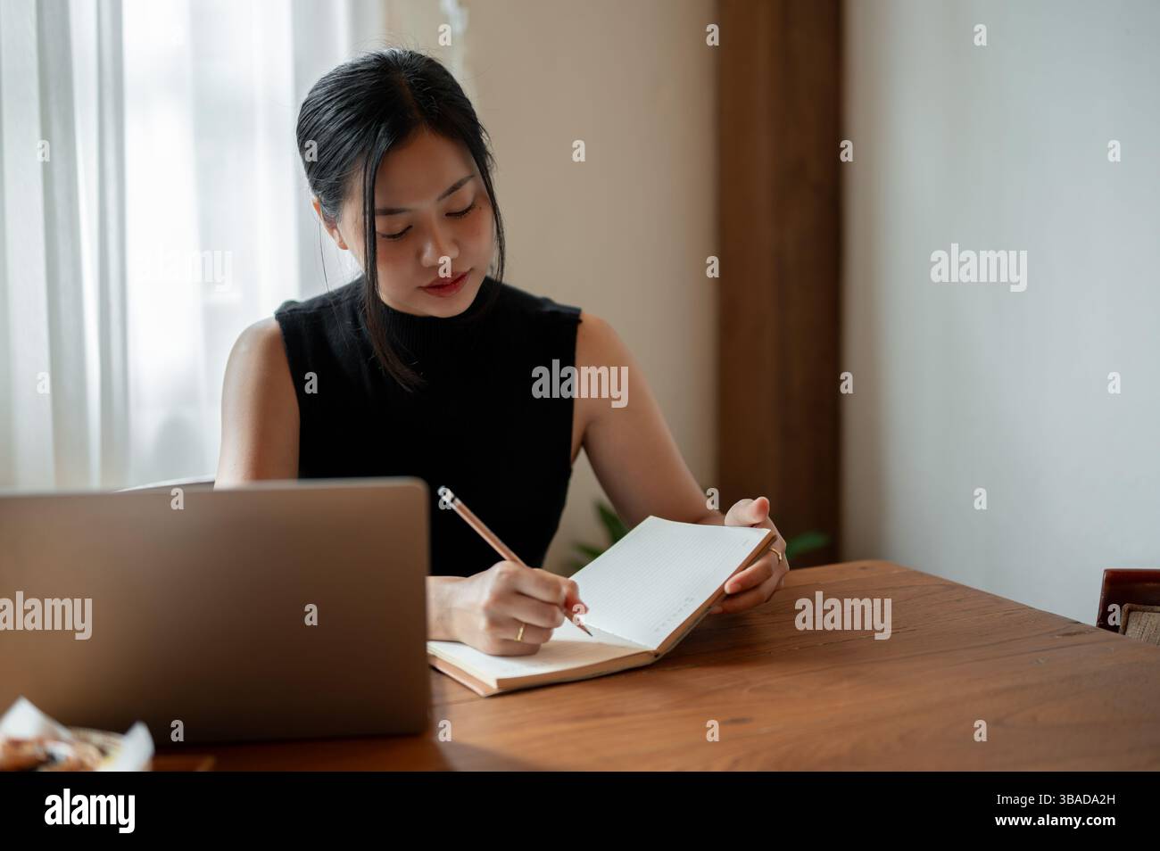 A beautiful millennial Asian woman working remotely at a coffee shop is ...