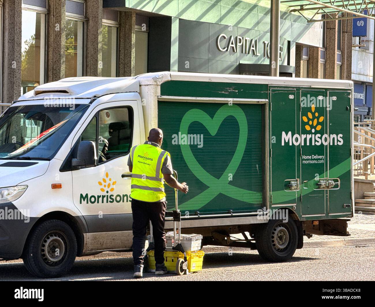 Cardiff, Wales, UK - 9 May 2025: Person working for the supermarket chain Morrisons delivering shopping to a building in Cardiff city centre - Smartphone Captured Stock Image