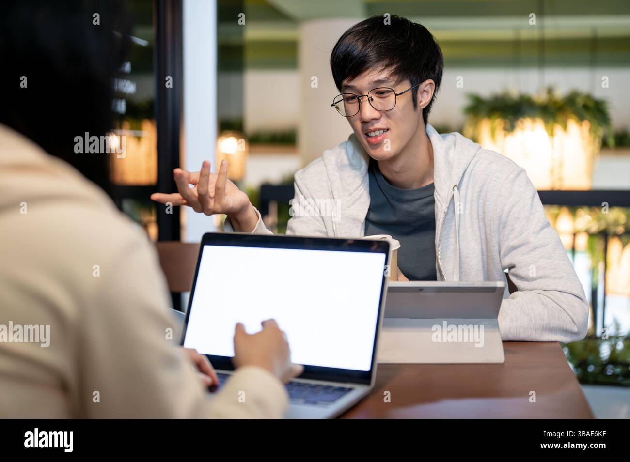 A young, happy Asian male college student is talking with his friend ...