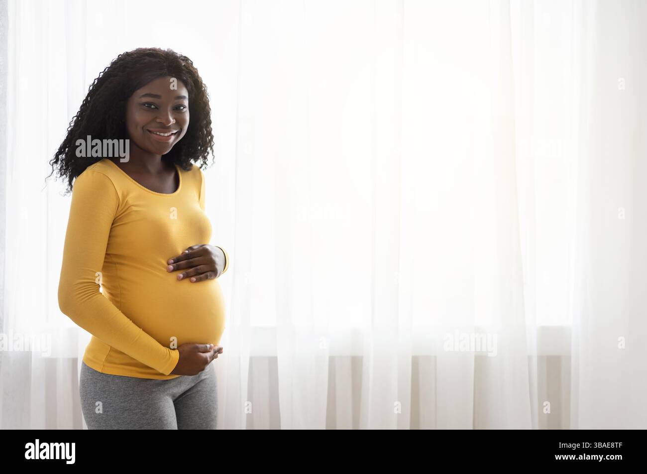Beautiful pregnant african american woman hugging her big belly ...