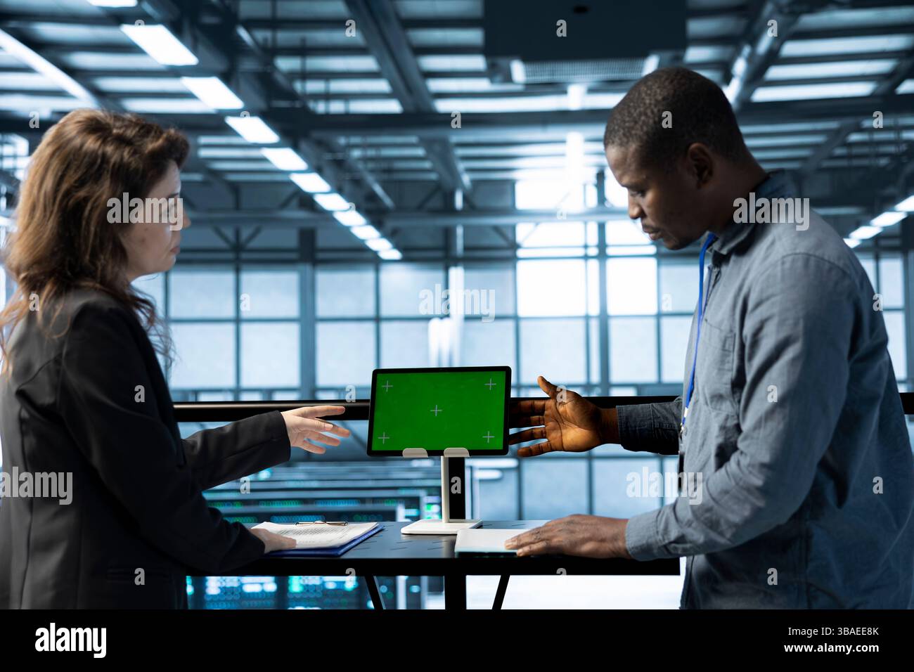 Software developers in data center using mockup tablet, observing analytics, reviewing equipment health. Server hub IT professionals talking, using chroma key device, adjusting system parameters Stock Photo