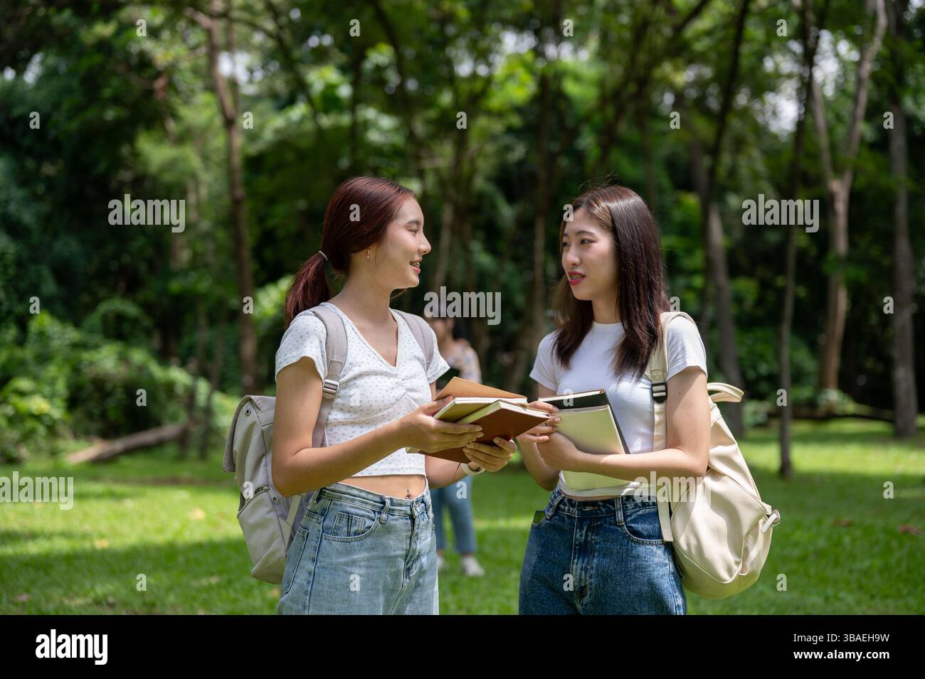Two pretty and happy young Asian female college students with backpacks ...
