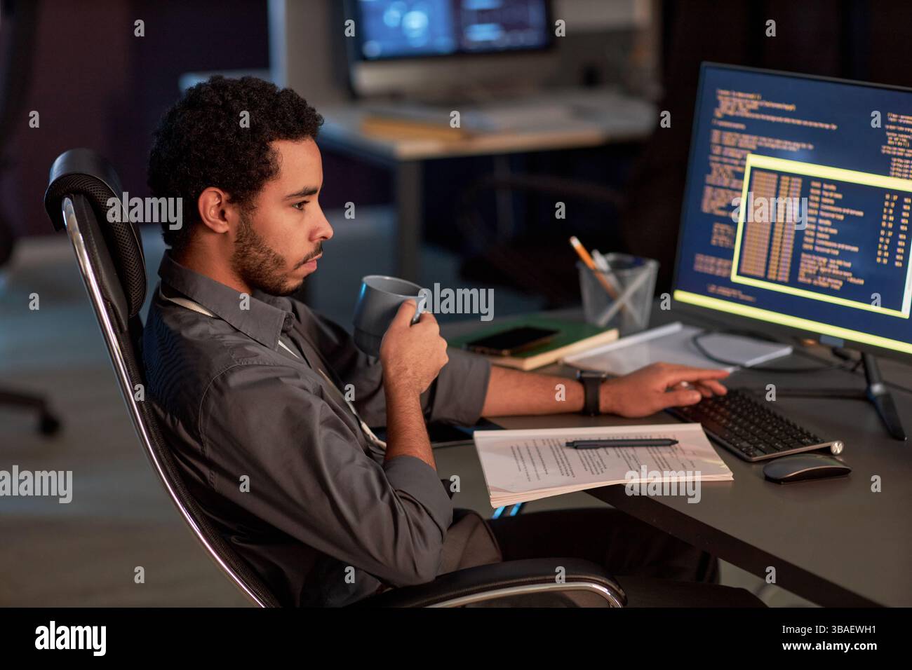 Side view portrait of male software developer writing code and drinking ...