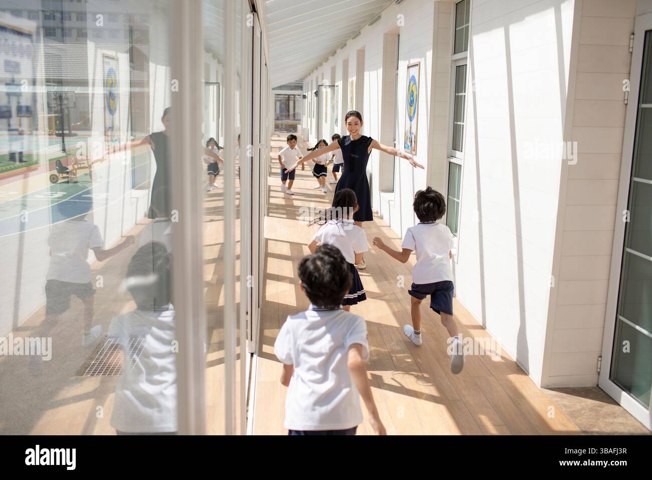 Chinese children running towards female teacher in school hallway Stock ...