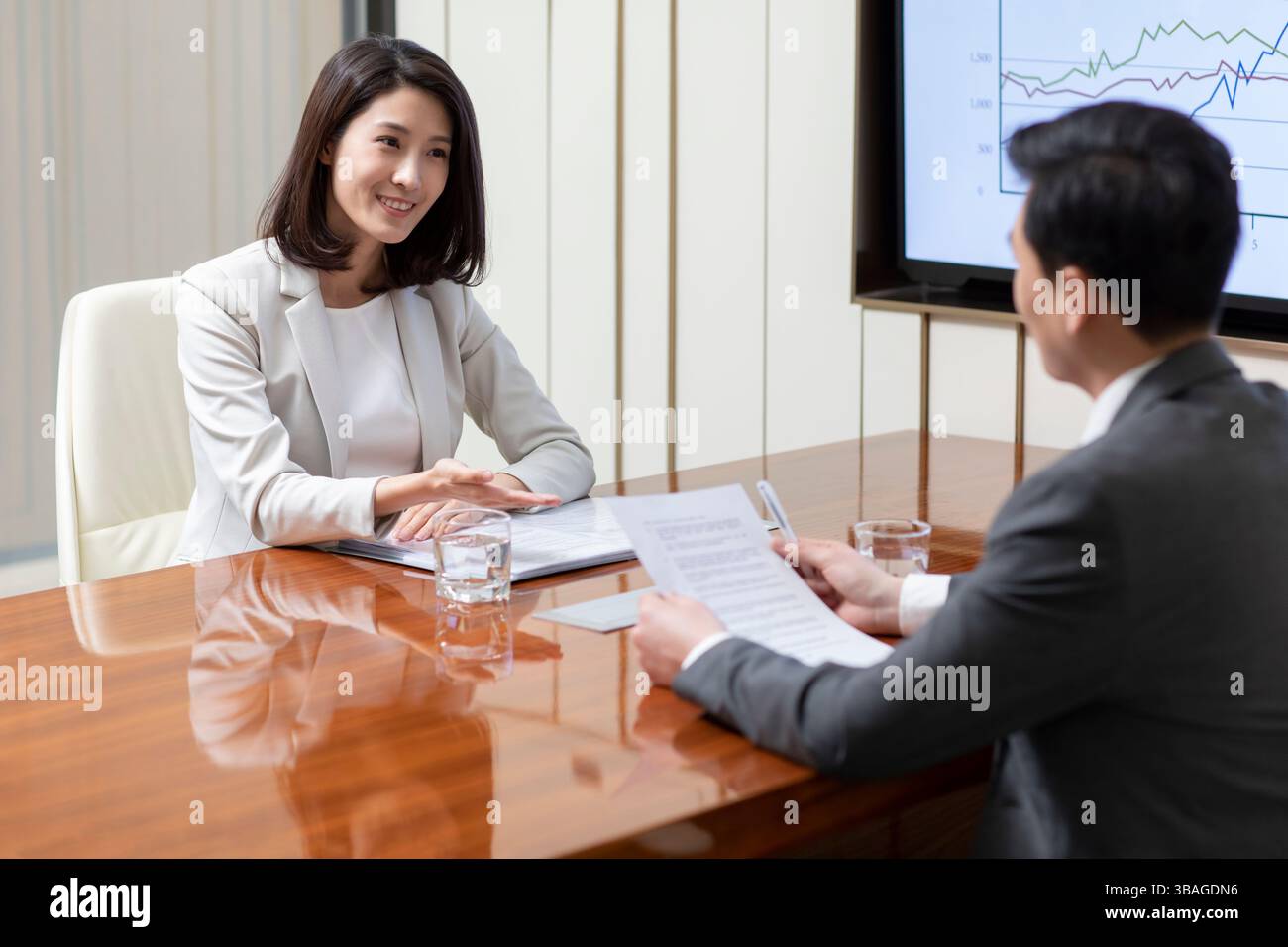 Smiling Chinese female candidate sitting at table looking at Asian male ...