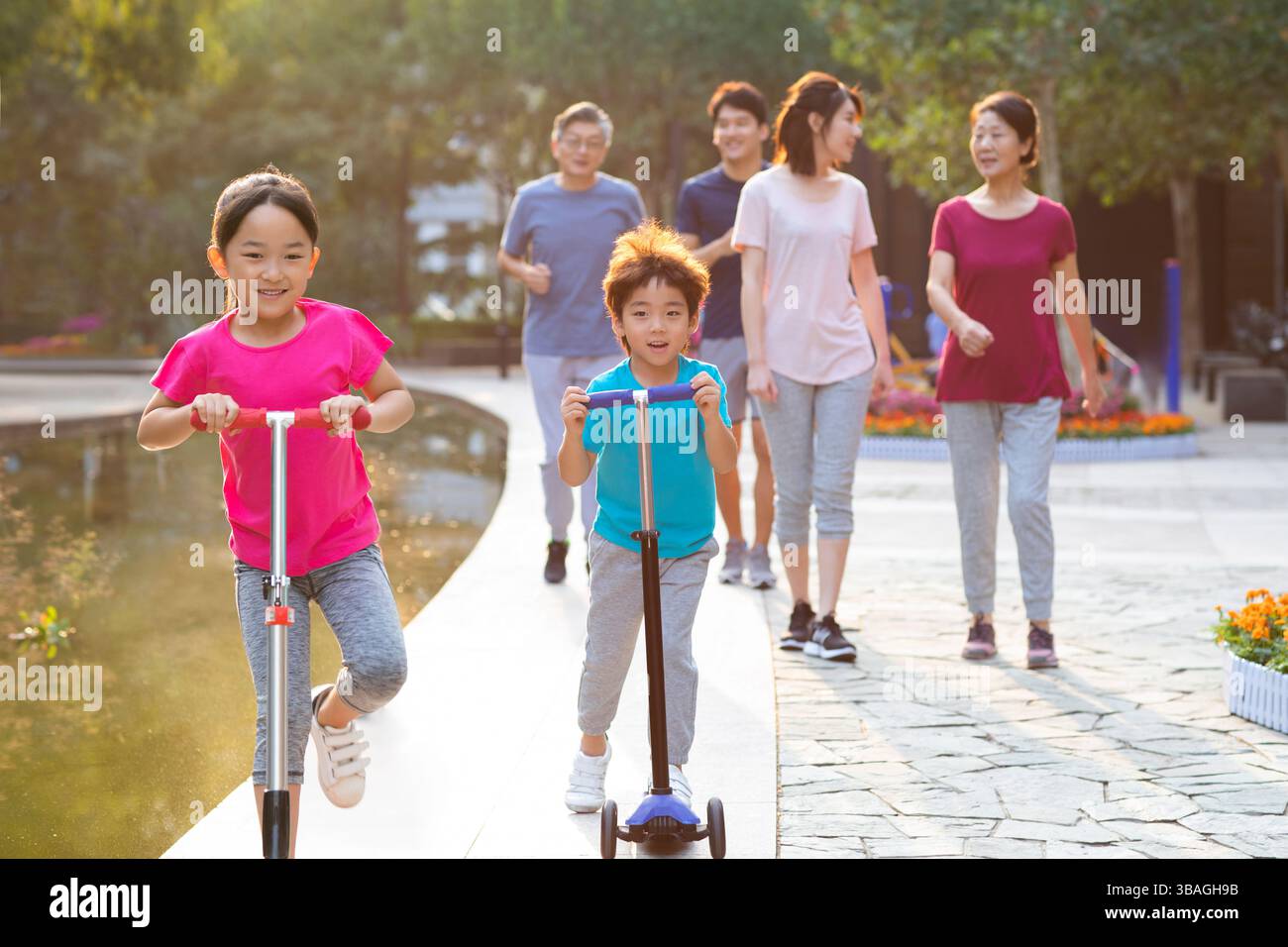 Chinese kids riding scooters while family watching them in park during ...