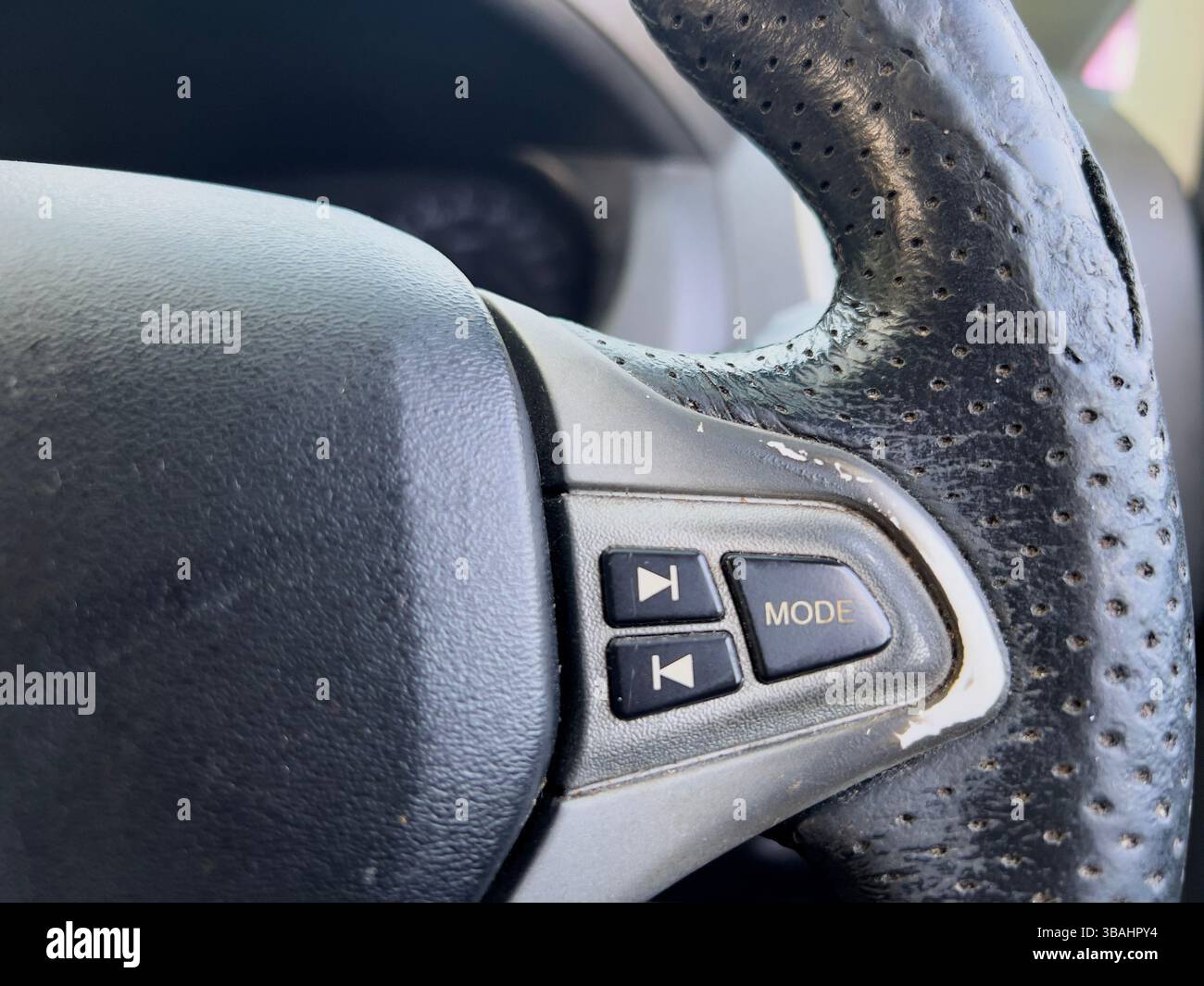 Detailed of a car steering wheel showing control buttons for mode and track selection. - Smartphone Captured Stock Image