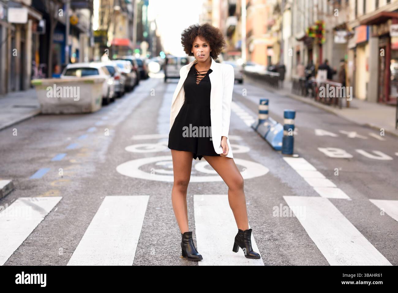 Young black woman with afro hairstyle walking on a crosswalk in an ...