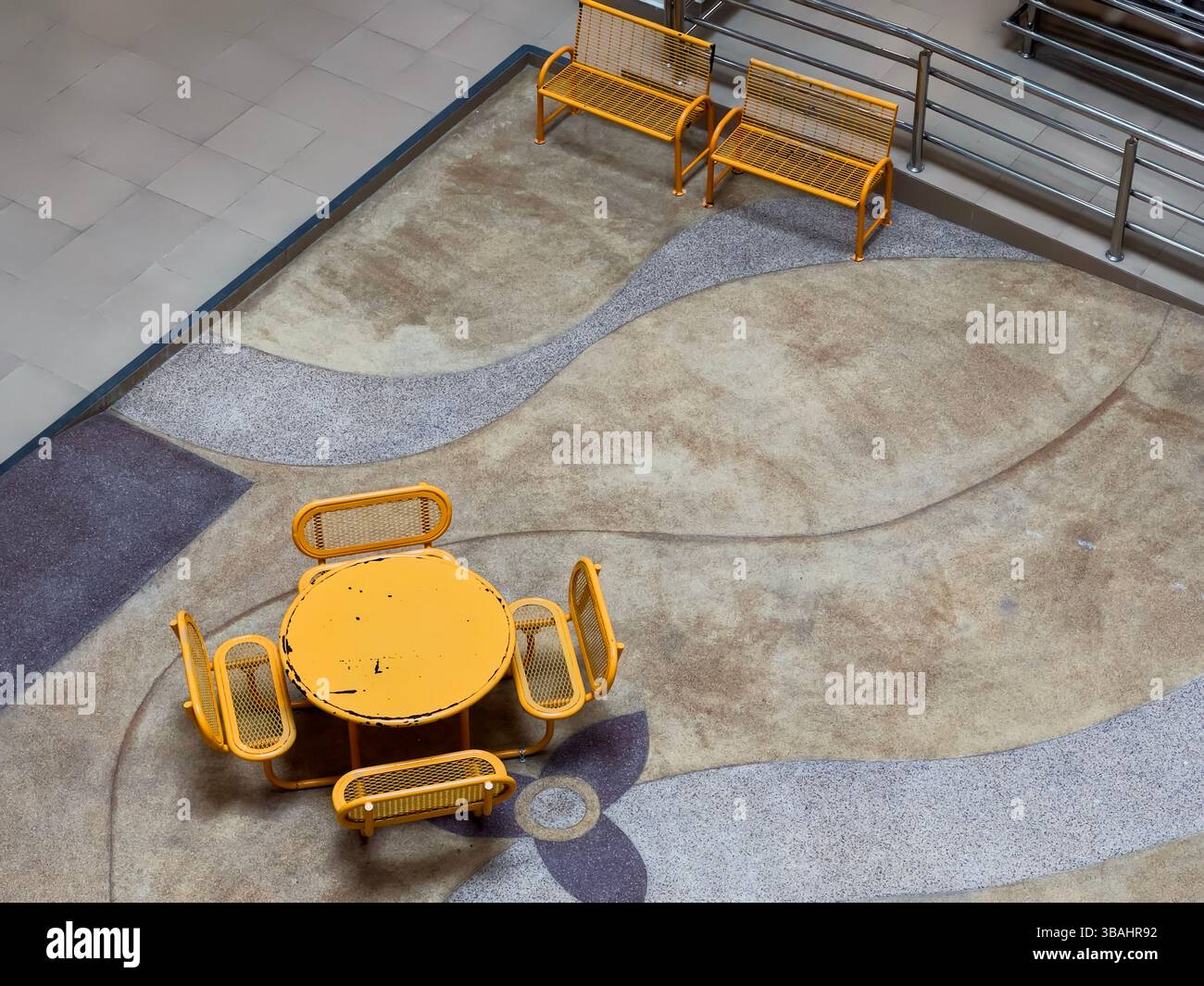 Top-down view of a stylish indoor seating area featuring a vibrant yellow round table, matching chairs, and sleek yellow benches. - Smartphone Captured Stock Image