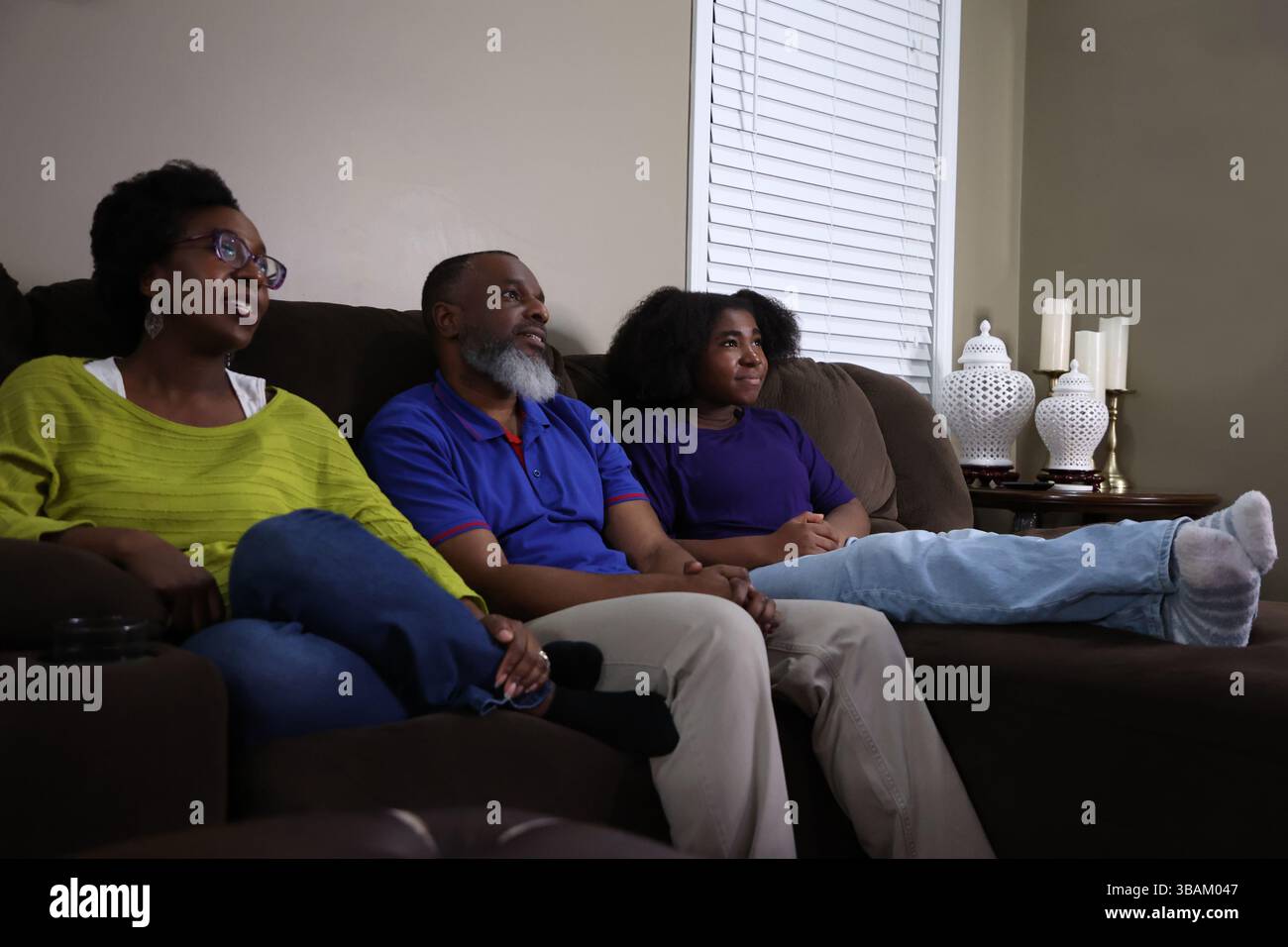 Black family sitting together on couch in living room at home Stock ...
