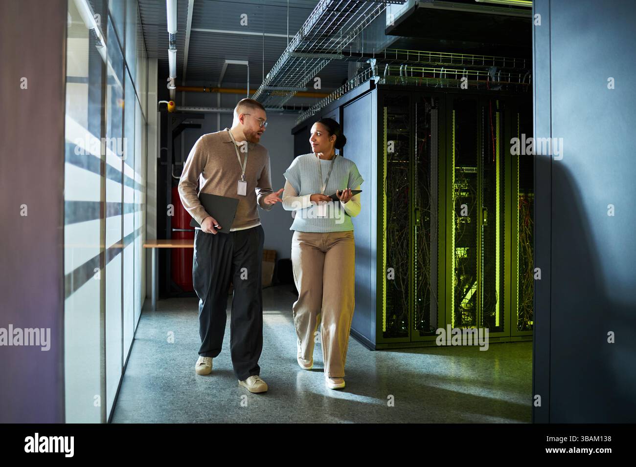 Colleagues Discussing Work while Walking in Server Room Stock Photo