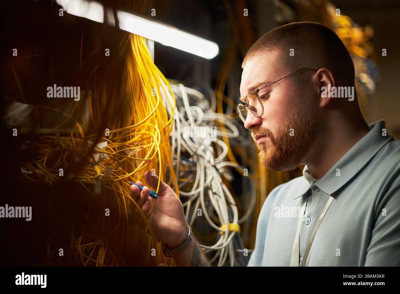 Man Working with Network Cables and Electronic Devices Stock Photo