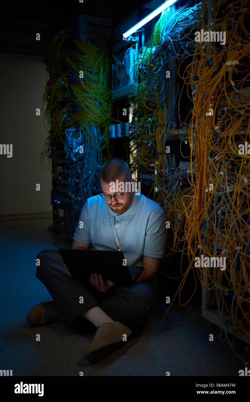 Technician Monitoring Network Cables in Server Room Stock Photo