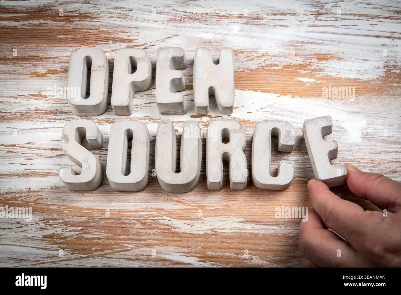 Open Source. Concrete alphabet letters on a light painted wood texture background. Stock Photo