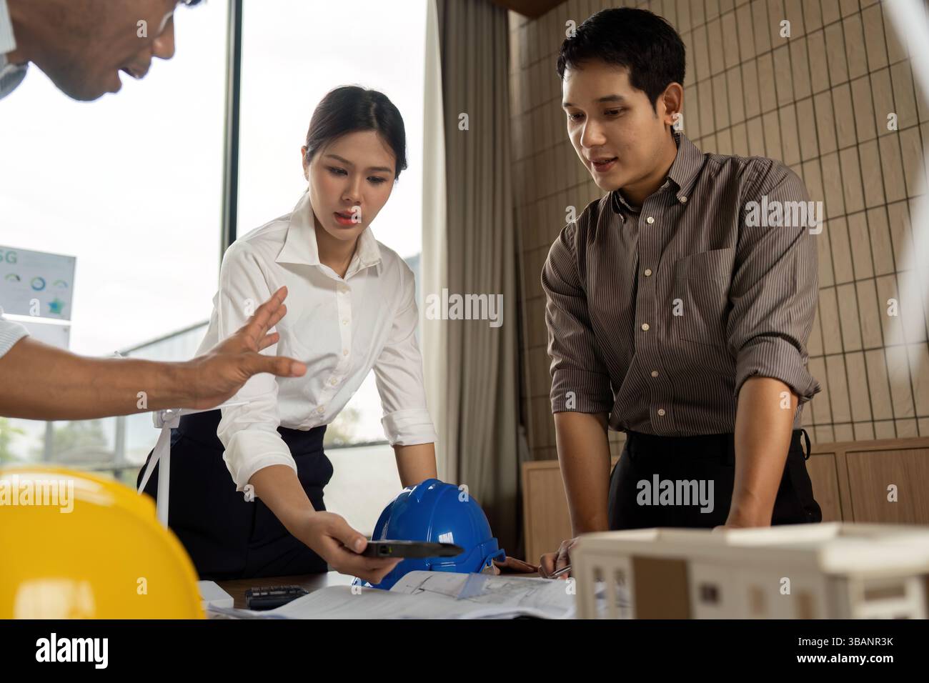 Sustainability engineers analyzing building plans in a collaborative environment Stock Photo