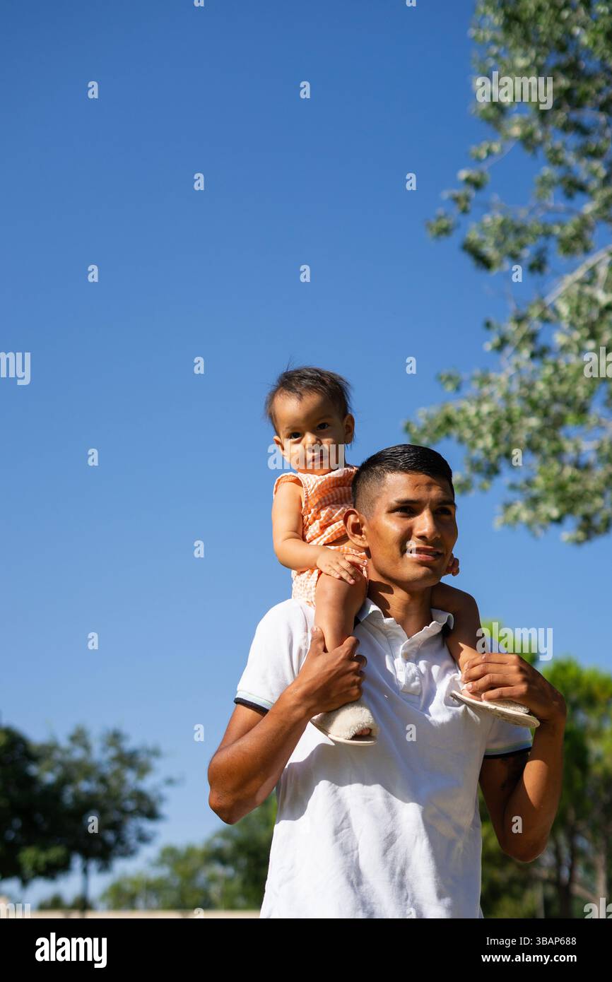 Peruvian Father Peruvian father with his baby on his shoulders walking through a park ...