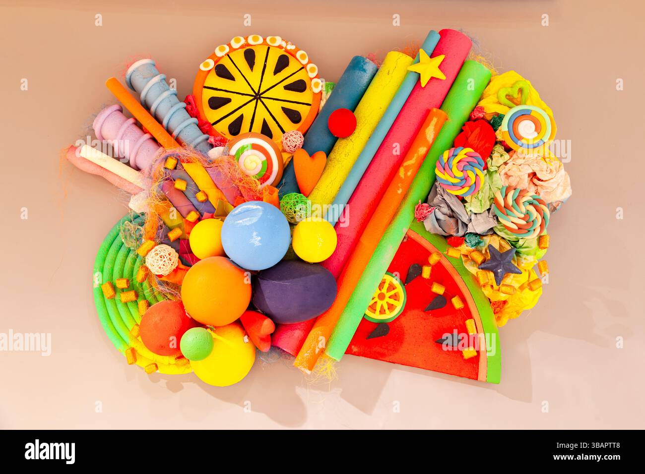 Colorful multicolored pattern on a pink wall made from various paper and plastic products. Stock Photo