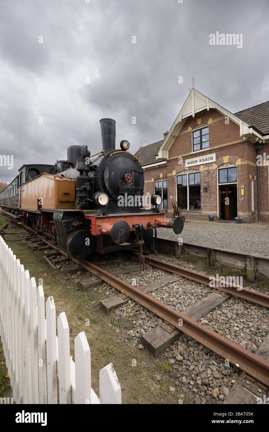 Vintage steam train parked on tracks in front of station building in ...