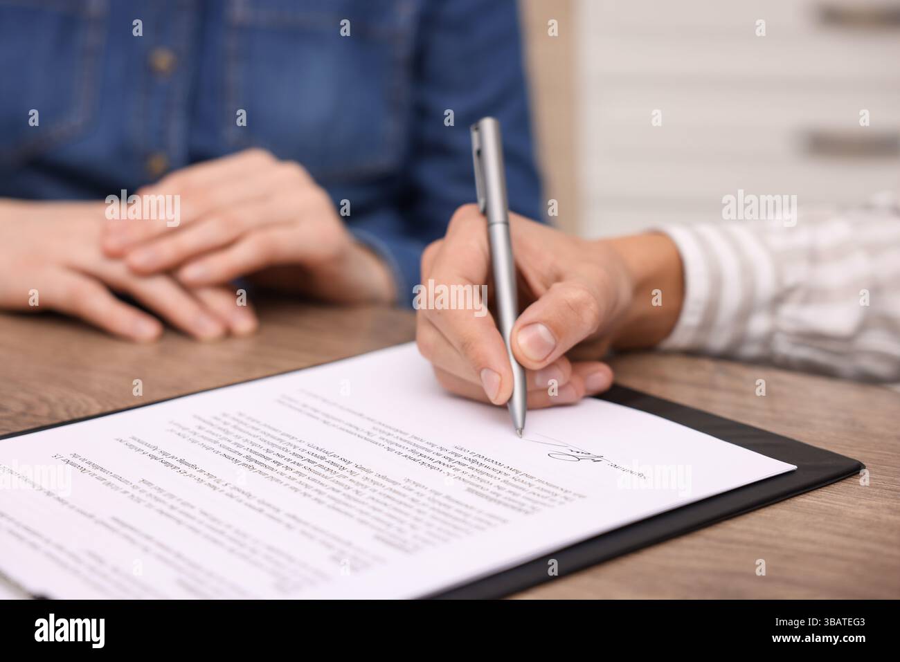 Man putting signature on document at table, closeup Stock Photo