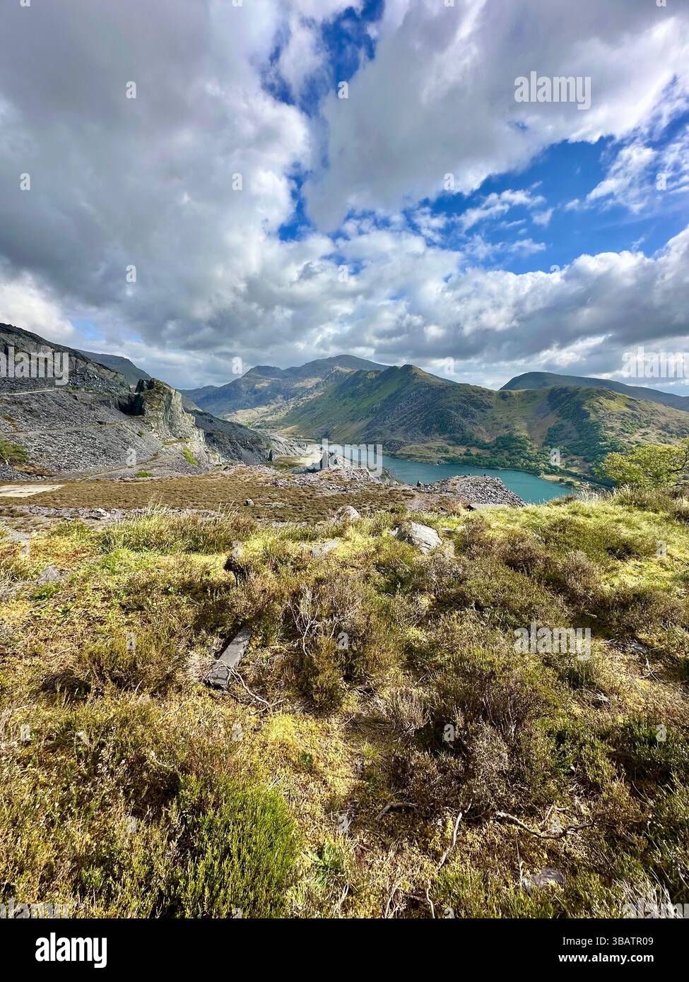 Scenic elevated view from Dinorwic Quarry overlooking Llyn Paris with the dramatic mountain landscape of Snowdonia in the background. Bright day. - Smartphone Captured Stock Image