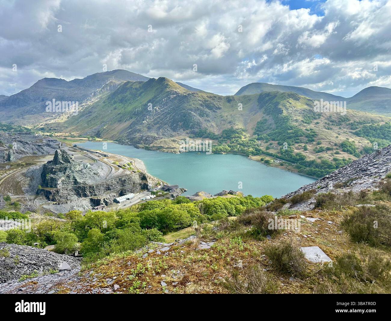 Scenic elevated view from Dinorwic Quarry overlooking Llyn Paris with the dramatic mountain landscape of Snowdonia in the background. Bright day. - Smartphone Captured Stock Image