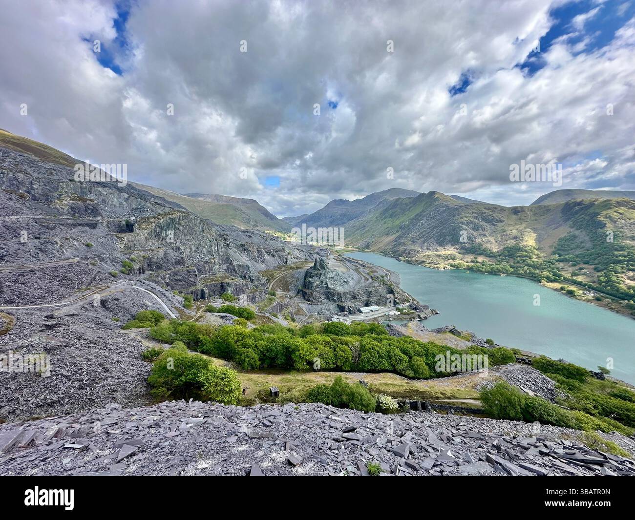 Scenic elevated view from Dinorwic Quarry overlooking Llyn Paris with the dramatic mountain landscape of Snowdonia in the background. Bright day. - Smartphone Captured Stock Image