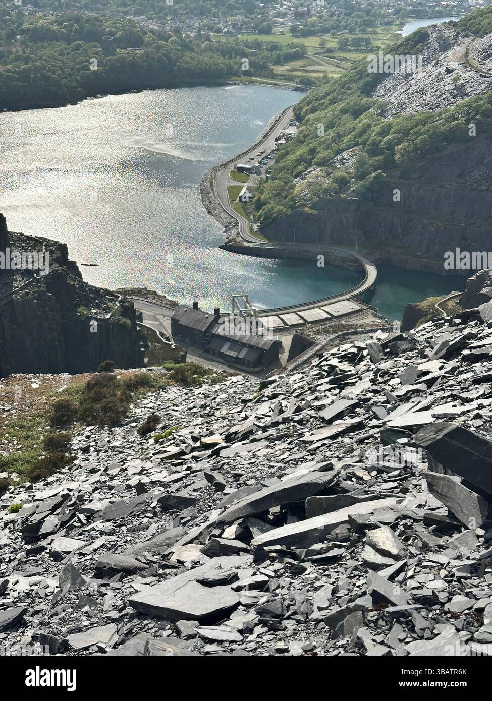 View from top of Dinorwic Quarry overlooking Dinorwic Power Station and Llyn Padarn, Llanberis, Wales. Slate foreground, no people. - Smartphone Captured Stock Image