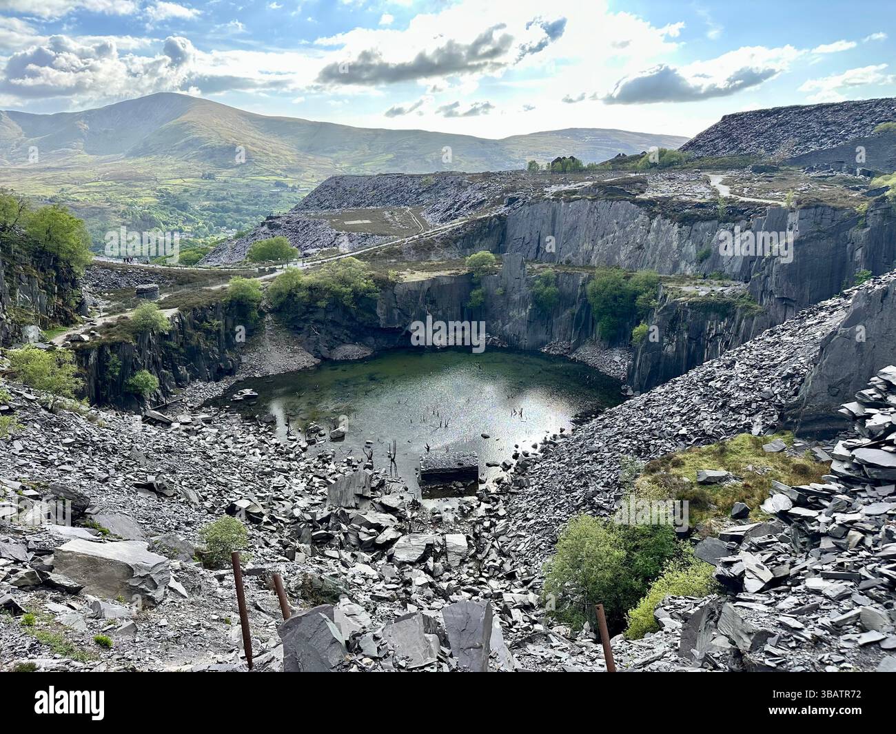 Looking down over Sinc Harriet (Dali’s Hole), a striking lagoon nestled in Dinorwic Quarry, Llanberis, North Wales with dramatic slate surroundings. - Smartphone Captured Stock Image