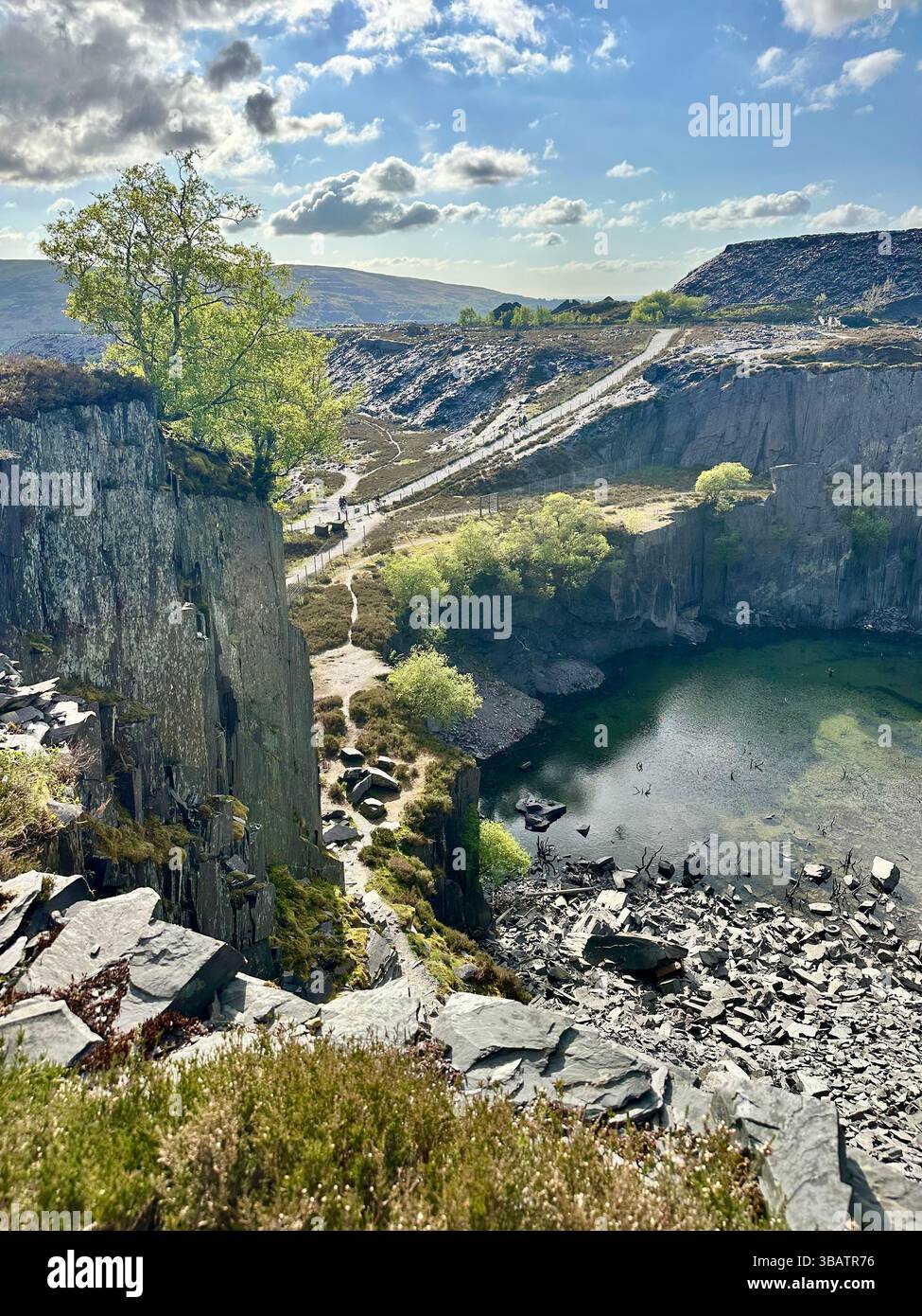 Looking down over Sinc Harriet (Dali’s Hole), a striking lagoon nestled in Dinorwic Quarry, Llanberis, North Wales with dramatic slate surroundings. - Smartphone Captured Stock Image