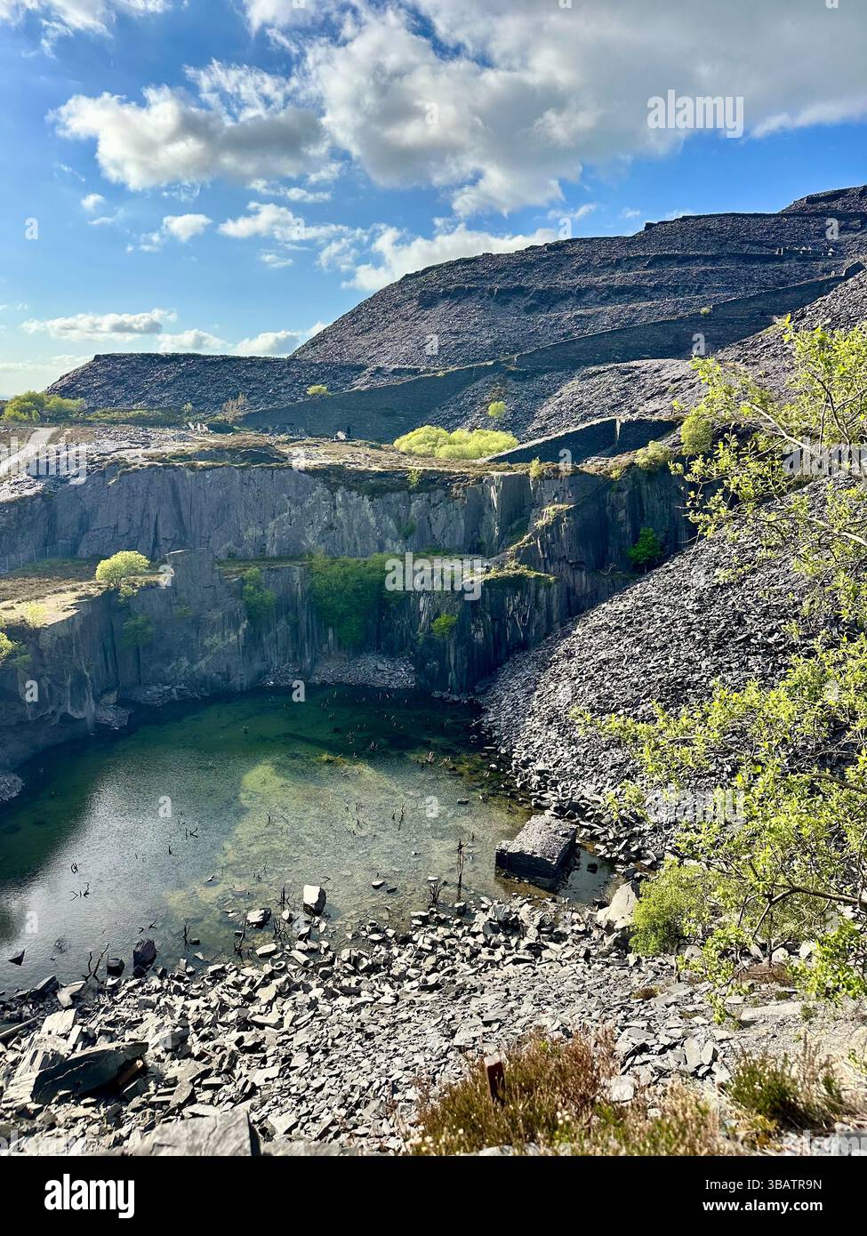 Looking down over Sinc Harriet (Dali’s Hole), a striking lagoon nestled in Dinorwic Quarry, Llanberis, North Wales with dramatic slate surroundings. - Smartphone Captured Stock Image